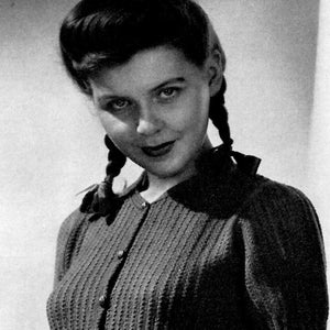 May include: A black and white photo of a woman wearing a knitted sweater with a button-up front and short sleeves. Her hair is styled in two braids.
