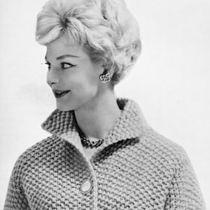 Può includere: Una donna con capelli corti e biondi indossa un cardigan di maglia grigio chiaro con chiusura a bottone. Il cardigan ha un motivo a maglia testurizzato e un colletto.