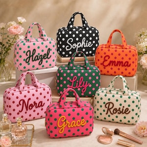 May include: A collection of rectangular zippered travel bags with top handles, each featuring a polka dot pattern and a personalized name embroidered on the front. The bags come in various colors including pink, black, orange, green, and cream.