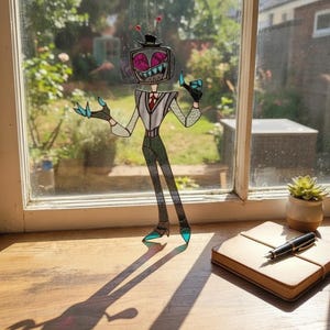 May include: A stained glass suncatcher depicting a character with a television head, wearing a top hat, vest, and tie. The figure has pink screen eyes, a wide grin, and teal-colored hands and shoes, suspended by a chain against a window.