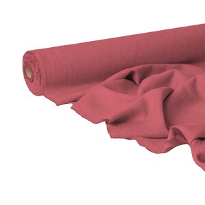 May include: A roll of dusty rose fabric, partially unrolled to reveal the soft texture. The fabric is draped in gentle folds, showcasing its flow and drape. Ideal for sewing and crafting projects.