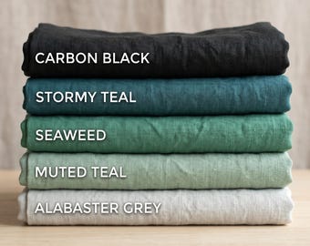 May include: A pile of folded linen fabric in shades of Carbon Black, Stormy Teal, Seaweed, Muted Teal, and Alabaster Grey. Each fabric has its colour name in white text. The fabrics are stacked on top of each other in a neat arrangement.