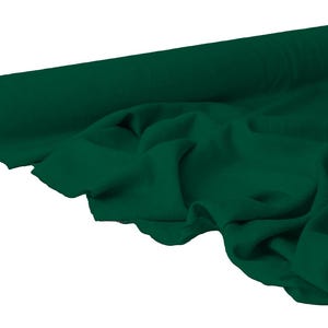 May include: A roll of dark green fabric, partially unrolled to reveal the soft texture. The fabric is a solid color, with visible folds and drapes, suggesting a flowing material. The roll is positioned on a white background.