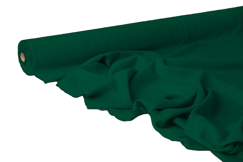 May include: A roll of dark green fabric, partially unrolled to reveal the soft texture. The fabric is a solid color, with visible folds and drapes, suggesting a flowing material. The roll is positioned on a white background.