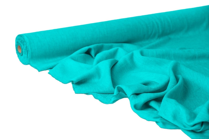 May include: A roll of turquoise fabric, partially unrolled to reveal the soft texture. The fabric is a solid color, with visible folds and creases. The roll is made of a cardboard core.