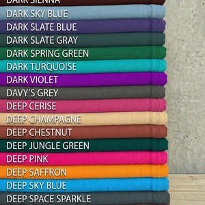 May include: A stack of fabric swatches in various colors, including dark sea green, dark sienna, and deep pink. Each swatch is labeled with its color name in white text. The fabrics appear to be folded neatly, showcasing a range of hues.