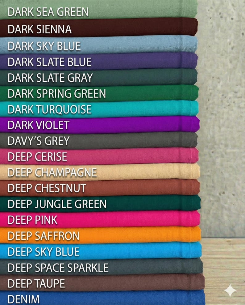 May include: A stack of fabric swatches in various colors, including dark sea green, dark sienna, and deep pink. Each swatch is labeled with its color name in white text. The fabrics appear to be folded neatly, showcasing a range of hues.