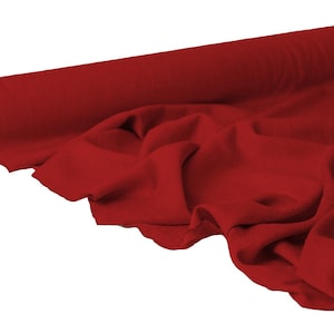 May include: A roll of vibrant red fabric, partially unrolled to reveal the soft texture. The fabric is draped, showing its folds and the way it catches the light. The roll is on the left side of the image, with the fabric extending to the right.