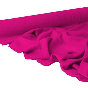 May include: A roll of vibrant fuchsia fabric, partially unrolled to reveal soft folds. The fabric is a solid color, with a smooth texture. Ideal for sewing, crafting, or other textile projects.