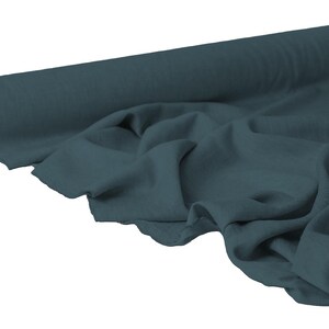 May include: A roll of teal fabric with a soft, flowing drape. The fabric is unrolled, revealing its texture and color. The roll is positioned on the left, with the unrolled fabric cascading to the right. Ideal for sewing and crafting projects.