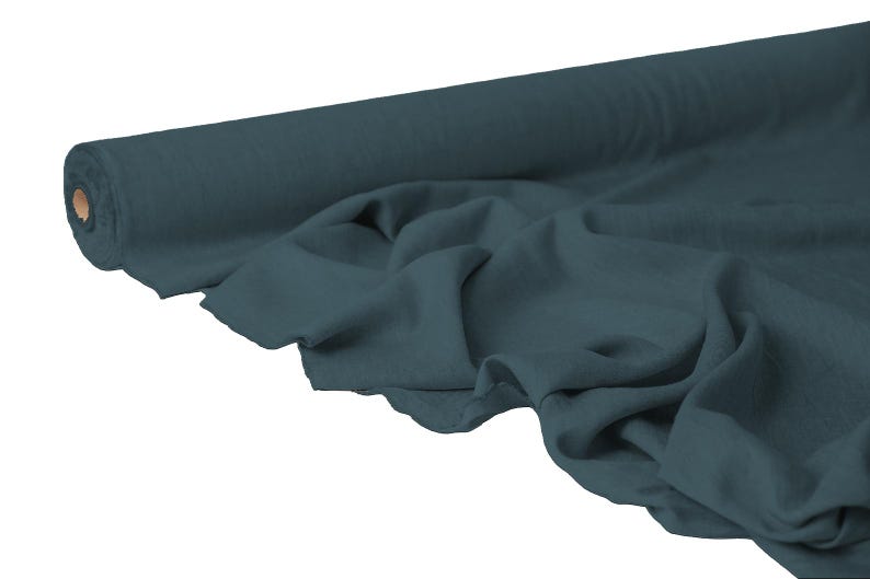 May include: A roll of teal fabric with a soft, flowing drape. The fabric is unrolled, revealing its texture and color. The roll is positioned on the left, with the unrolled fabric cascading to the right. Ideal for sewing and crafting projects.