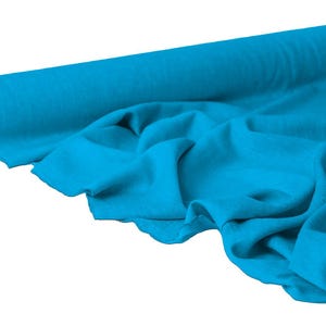 May include: A roll of vibrant turquoise fabric, partially unrolled to reveal soft folds. The fabric is a solid color, with a slight sheen, suggesting a smooth texture. The roll is made of cardboard.