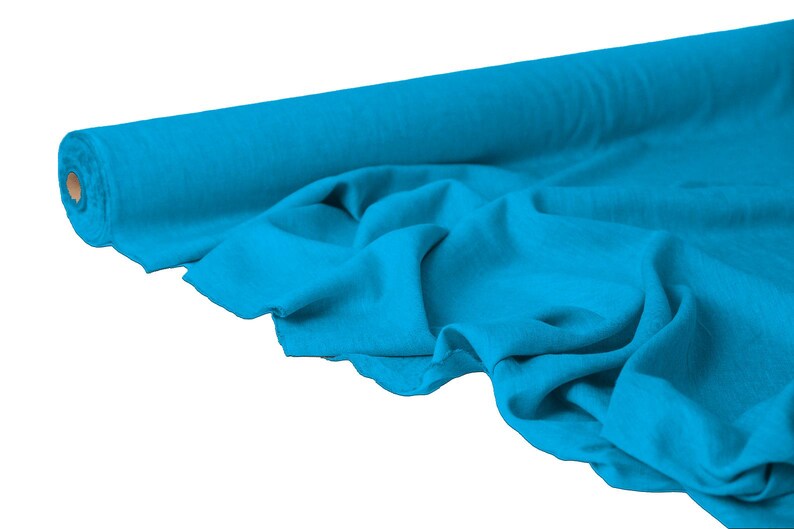May include: A roll of vibrant turquoise fabric, partially unrolled to reveal soft folds. The fabric is a solid color, with a slight sheen, suggesting a smooth texture. The roll is made of cardboard.