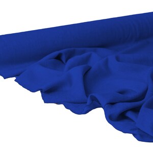 May include: A roll of vibrant blue fabric, partially unrolled to reveal soft folds. The fabric is a solid, rich blue color, and the roll's core is visible at the end. The material appears to be lightweight and suitable for various sewing projects.