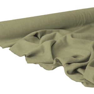 May include: A roll of olive green fabric with a soft, textured appearance. The fabric is draped, showing its flowing quality. The roll is partially unraveled, revealing the material's texture and color.