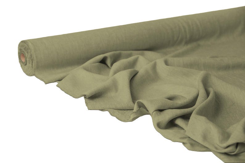 May include: A roll of olive green fabric with a soft, textured appearance. The fabric is draped, showing its flowing quality. The roll is partially unraveled, revealing the material's texture and color.