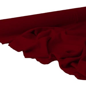 May include: A roll of deep burgundy fabric, partially unrolled to reveal soft folds. The fabric is a rich, solid color, with a slight sheen, suggesting a luxurious material suitable for apparel or home decor projects.