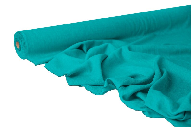 May include: A roll of turquoise fabric with a visible texture. The fabric is partially unrolled, revealing soft folds and a glimpse of the cardboard core. The color is a vibrant teal, suitable for various sewing and crafting projects.