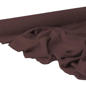 May include: A roll of dark brown fabric, partially unrolled to reveal the soft, draped material. The fabric is a solid color, with visible texture and folds. The roll is positioned on the left side of the image.
