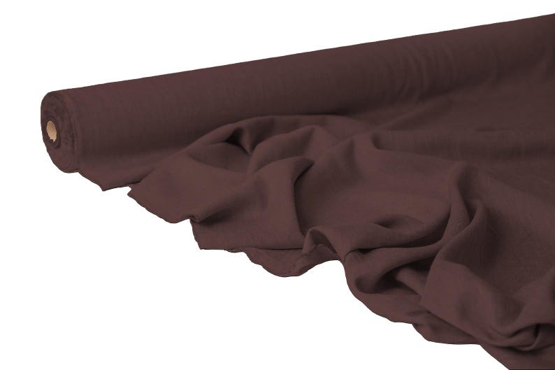 May include: A roll of dark brown fabric, partially unrolled to reveal the soft, draped material. The fabric is a solid color, with visible texture and folds. The roll is positioned on the left side of the image.