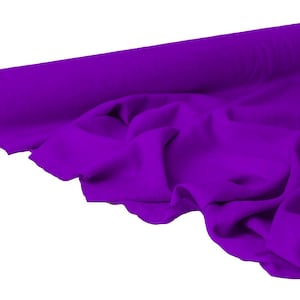 May include: A roll of vibrant purple fabric, partially unrolled to reveal soft folds. The fabric is a solid color, with a smooth texture. The roll is positioned on the left side of the image, with the unrolled fabric cascading towards the right.