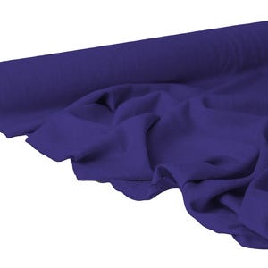 May include: A roll of deep purple fabric, partially unrolled to reveal the draped material. The fabric is a solid color, with visible folds and soft shadows, suggesting a flowing texture. The roll is cylindrical with a cardboard core.