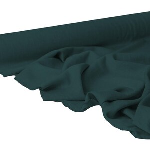 May include: A roll of dark teal fabric with a soft, draped appearance. The fabric is unrolled, revealing its texture and color. Ideal for sewing projects, the fabric is a solid color and appears to be a medium weight.
