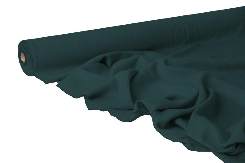 May include: A roll of dark teal fabric with a soft, draped appearance. The fabric is unrolled, revealing its texture and color. Ideal for sewing projects, the fabric is a solid color and appears to be a medium weight.