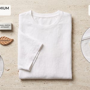 May include: A white short-sleeve t-shirt with text labels reading DEFINITIVE PREMIUM CONSTRUCTION and ULTIMATE FINISH & DETAIL. Includes a small-batch artisanry tag, a sustainable leaf-shaped icon, and a label stating PURE EUROPEAN LINEN 100% Linen Hand-Sewn.