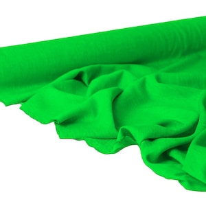 May include: A roll of bright green fabric, partially unrolled to reveal the soft texture. The fabric is a vibrant, solid green color, with visible folds and drapes. The roll is positioned on the left side of the image.