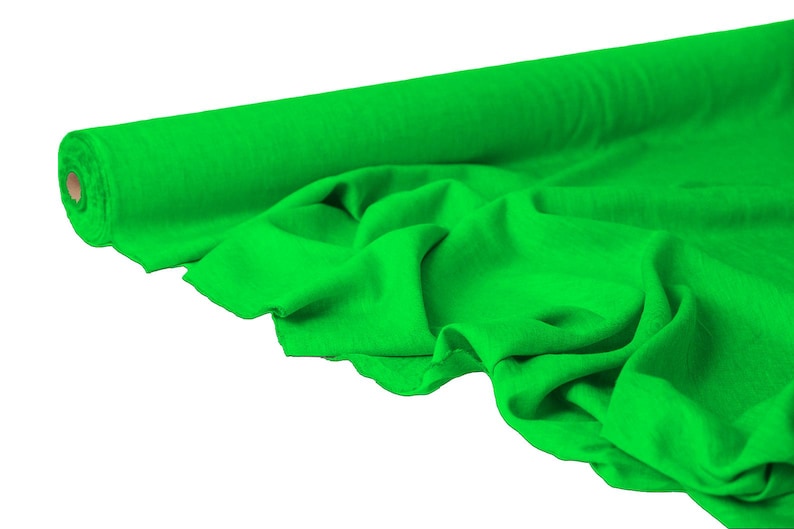 May include: A roll of bright green fabric, partially unrolled to reveal the soft texture. The fabric is a vibrant, solid green color, with visible folds and drapes. The roll is positioned on the left side of the image.