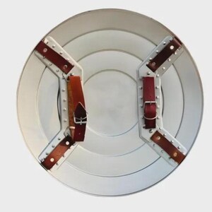 May include: A silver-colored, round shield with concentric circles. It features brown leather straps and silver metal brackets secured with rivets. The shield has a classic, vintage design.