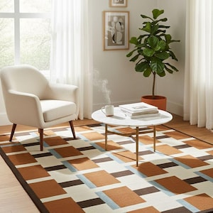 May include: A modern living room scene featuring a geometric patterned rug in shades of brown, cream, and blue. A white armchair, a round coffee table, and a potted plant complete the cozy interior design.