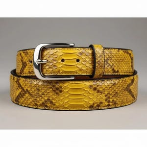 May include: A yellow and brown snakeskin belt with a silver buckle. The belt is made of genuine snakeskin and has a classic design. The belt is approximately 1.5 inches wide.