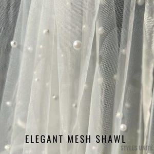 May include: White mesh shawl with scattered faux pearls. The text "ELEGANT MESH SHAWL" is displayed at the bottom of the image. The shawl is draped, creating soft folds and shadows. The overall effect is delicate and elegant.