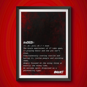 Puede incluir: Impresión artística enmarcada con marco negro, con la palabra "AuDHD" en texto blanco sobre un fondo rojo oscuro. La impresión incluye una definición y descripción de AuDHD, con el logotipo ØNQUIET en la parte inferior.
