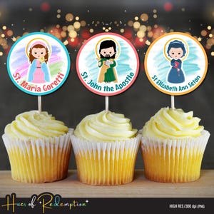 Op de afbeelding: Drie cupcakes met gele glazuur, elk bekroond met een rond beeld van een heilige. De afbeeldingen omvatten St. Maria Goretti, St. John the Apostle en St. Elizabeth Ann Seton. De tekst "Hues of Redemption" staat onderaan.