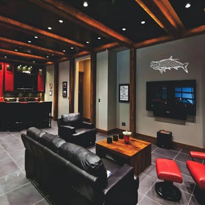 May include: A modern living room with a black leather sofa, two black armchairs, and a wooden coffee table. The room features a large flat-screen TV, a decorative fish outline, and red accent chairs. The ceiling has exposed wooden beams.