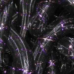 May include: A flexible, tubular mesh material featuring a dense black woven structure interwoven with thin, reflective purple metallic ribbons that create a repeating diagonal pattern across the surface of the coiled, cylindrical material.