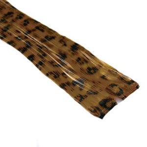 Puede incluir: Una extensión de pelo con estampado de leopardo marrón y negro. La extensión está hecha de pelo sintético y está diseñada para añadir longitud y volumen a tu cabello.