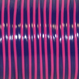 May include: A spool of cord featuring a repeating pattern of vertical stripes in alternating colors of deep navy blue and vibrant hot pink. The material has a smooth, glossy finish that reflects light, creating a consistent linear texture.