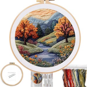 May include: A completed embroidery landscape scene in a wooden hoop. The scene depicts a river flowing through a valley with trees in autumn colors. Additional supplies include a blank hoop, pattern, and embroidery floss.