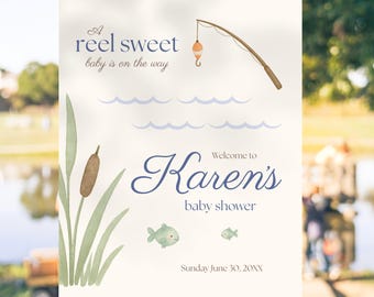 Op de afbeelding: Een babyborrelbord op een ezel met een visthema. Het bord leest "A reel sweet baby is on the way" en "Welcome to Karen's baby shower". Het bord bevat illustraties van een hengel, vissen en lisdodden.
