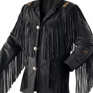 Könnte beinhalten: Eine schwarze Lederjacke mit langen Fransen an Brust, Rücken und Ärmeln. Die Jacke verfügt über drei silberfarbene Metallknöpfe auf der Vorderseite, dekorative geflochtene Lederverzierungen sowie kreisförmige Perlenakzente an den Schultern und Ärmeln.