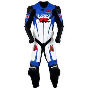 Pode incluir: Um fato de corrida de mota de corpo inteiro em branco, azul e preto. O fato apresenta o logótipo da Suzuki e a marca GSX em vermelho e preto no peito, ombros e pernas. Inclui acolchoamento protetor nos ombros e nos joelhos.
