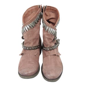 May include: A pair of dusty rose-colored suede boots. The boots have a short shaft with silver-toned metal accents along the top and a strap with silver studs around the ankle. The boots have a zipper closure on the side.