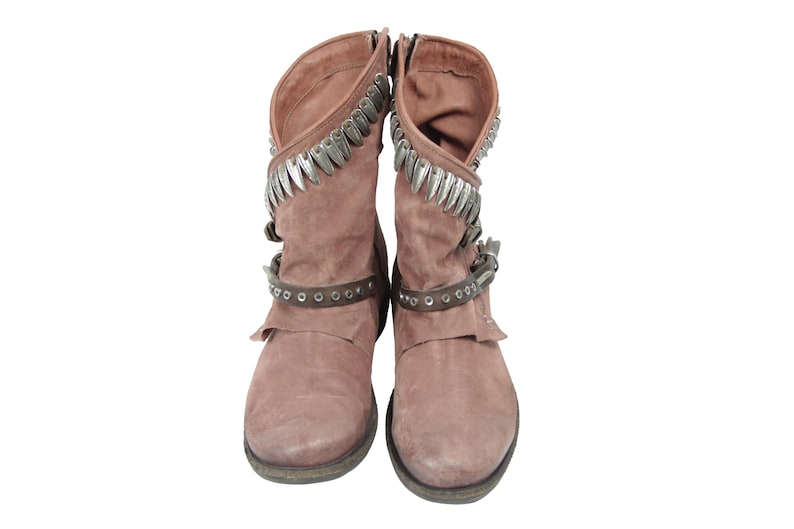 May include: A pair of dusty rose-colored suede boots. The boots have a short shaft with silver-toned metal accents along the top and a strap with silver studs around the ankle. The boots have a zipper closure on the side.