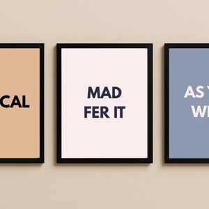 Puede incluir: Tres impresiones enmarcadas con marcos negros. Las impresiones presentan las palabras "BIBLICAL" sobre un fondo beige, "MAD FER IT" sobre un fondo blanco y "AS YOU WERE" sobre un fondo azul.