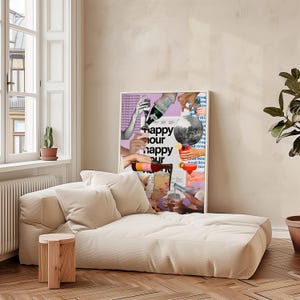 May include: A cream-colored chaise lounge with two matching pillows and a small wooden side table. A framed poster with the words "happy hour" and images of cocktails hangs on the wall. A potted cactus and a plant are also visible.
