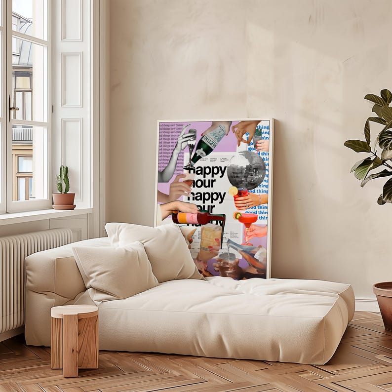 May include: A cream-colored chaise lounge with two matching pillows and a small wooden side table. A framed poster with the words "happy hour" and images of cocktails hangs on the wall. A potted cactus and a plant are also visible.